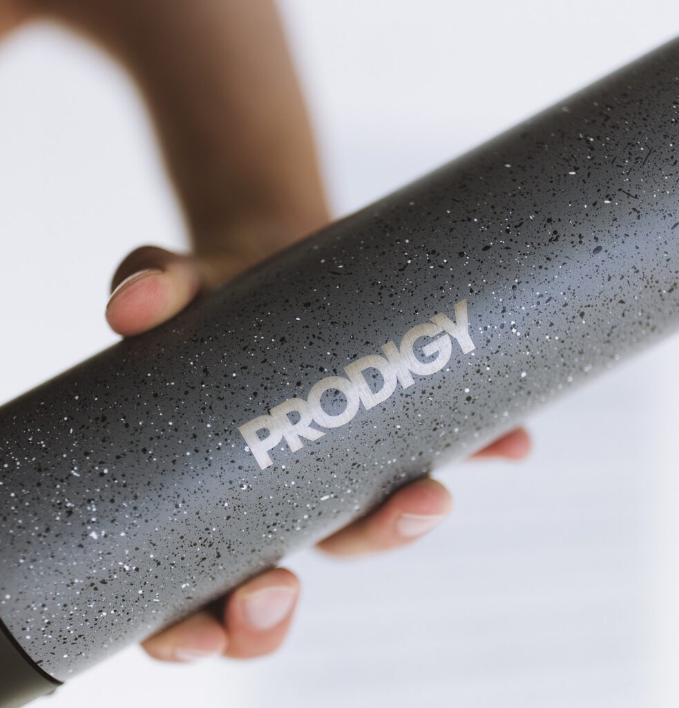 Hand holding a speckled gray insulated water bottle with an engraved logo