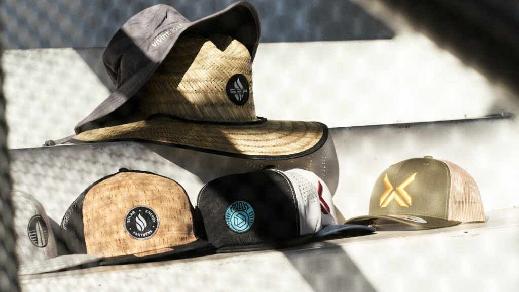 Custom-patched straw hats and trucker caps lined up on bleachers