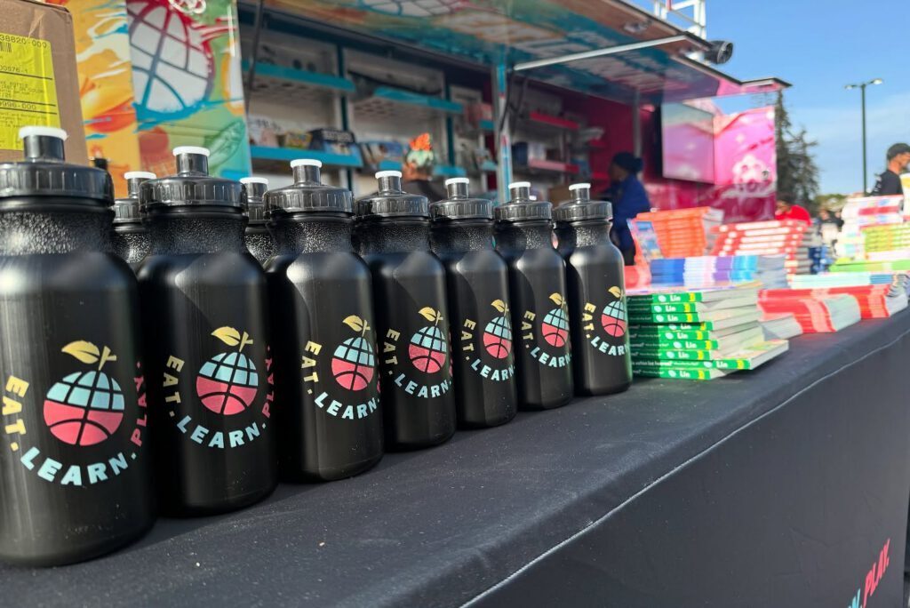 Eat Learn Play branded black water bottles laid out at a youth fun run