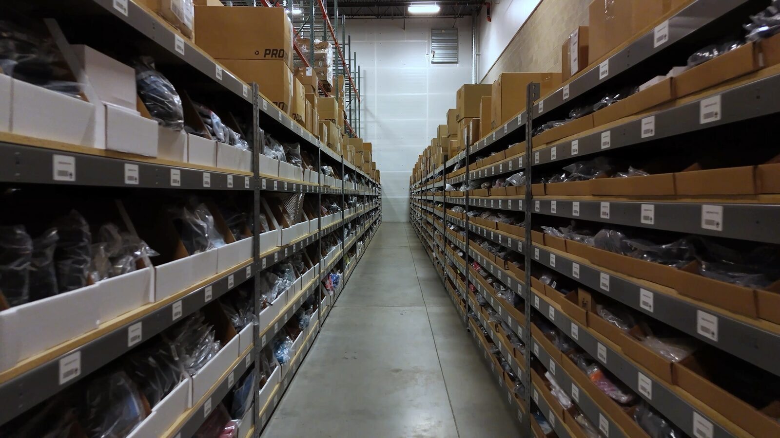 An aisle of warehouse racking stocked with bagged, boxed webstore inventory at Prodigy Promos' FlexONE fulfillment center in Lindon, Utah