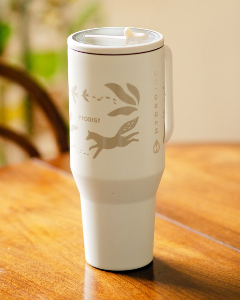 Laser-engraved fox artwork on a cream insulated tumbler with handle