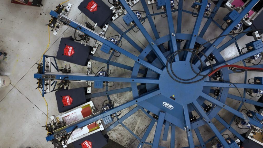 Overhead view of Prodigy Promos' automatic screen-printing carousel running a Total Archery Challenge job