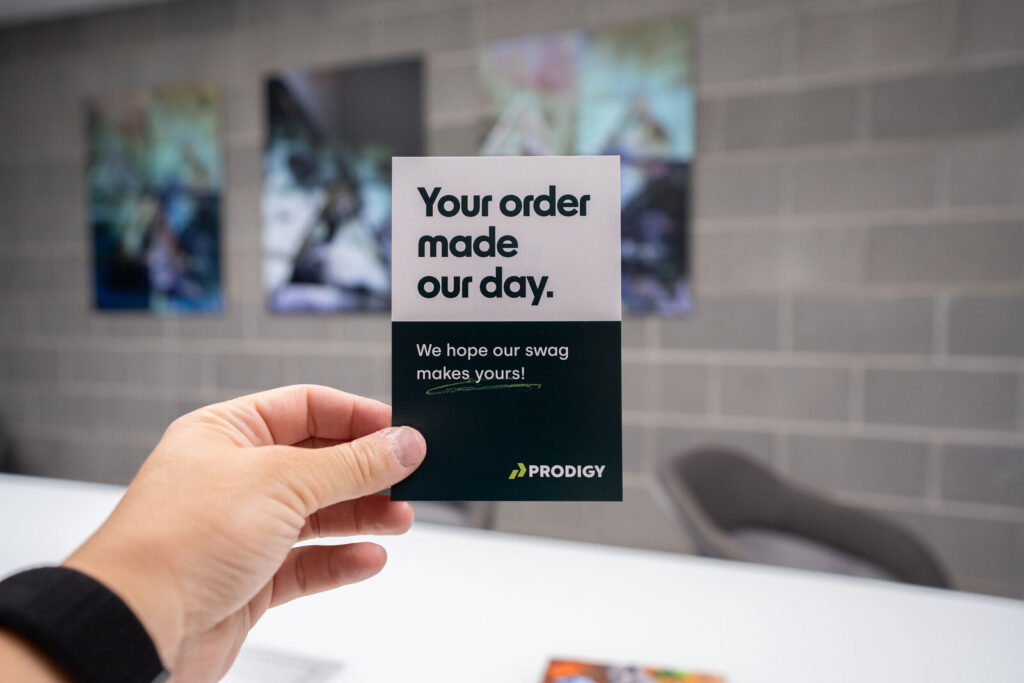 A hand holding a Prodigy insert card reading "Your order made our day"