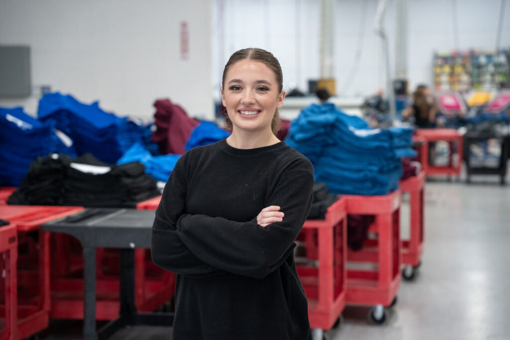 A Prodigy team member with carts of undecorated blank apparel staged for production