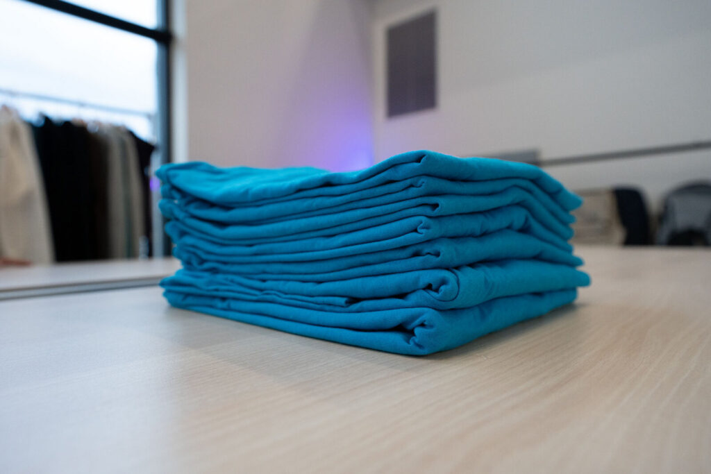 A stack of folded teal branded tees ready for a uniform program