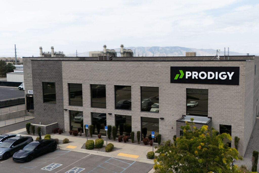 The Prodigy Promos headquarters in Lindon, Utah, a two-storey grey brick building with the PRODIGY sign and the Wasatch range behind it